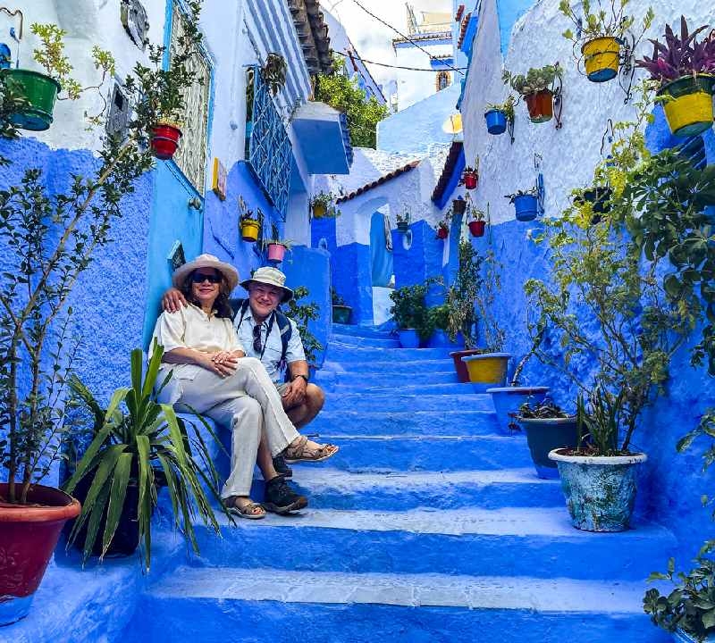 Casal maduro posando em uma escadaria em Chefchaouen, Marrocos. As coloridas muralhas azuis da cidade tornam esta cidade única. Casal maduro posando em uma escadaria em Chefchaouen, Marrocos. As coloridas muralhas azuis da cidade tornam esta cidade única.