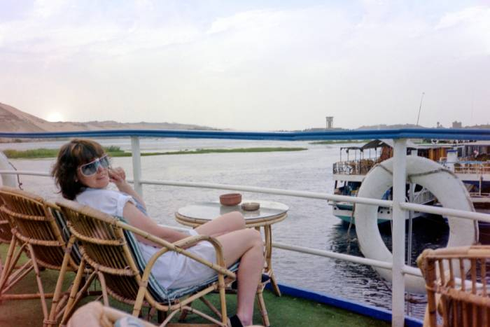 Traveler relaxing on a traditional Dahabiya Nile cruise while enjoying scenic river views in Egypt.