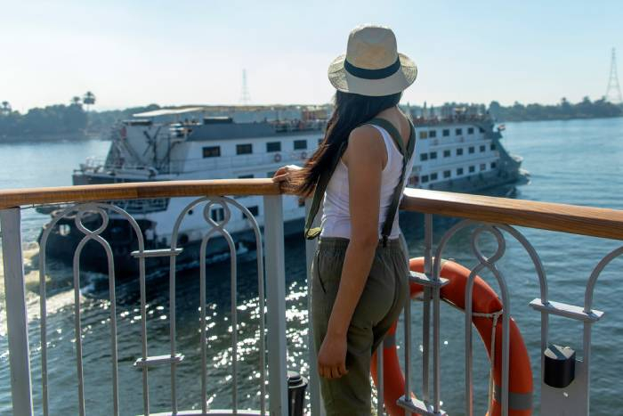 Traveler enjoying the view from a Nile River cruise ship as another cruise vessel passes by in Egypt.