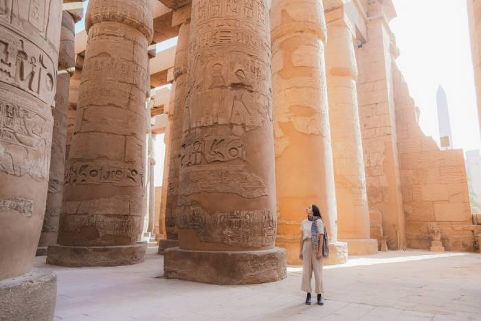 Traveler exploring the towering ancient columns and hieroglyphs inside Karnak Temple in Luxor, Egypt.