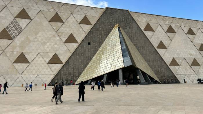 Visitors entering the Grand Egyptian Museum through its iconic pyramid-shaped entrance in Giza.