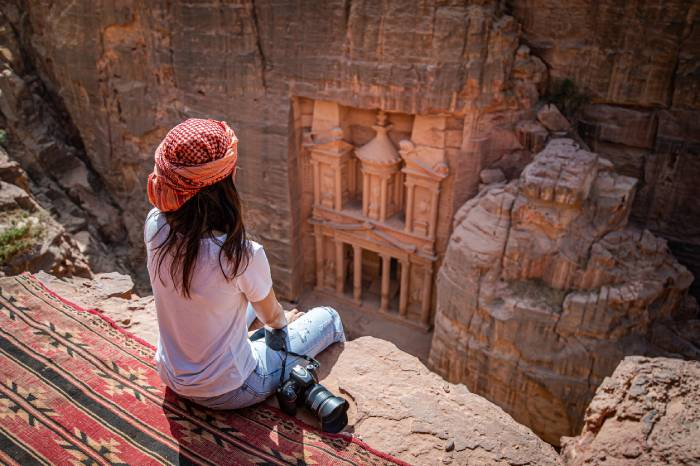 Traveler overlooking the iconic Treasury (Al-Khazneh) from a scenic viewpoint in Petra, Jordan.