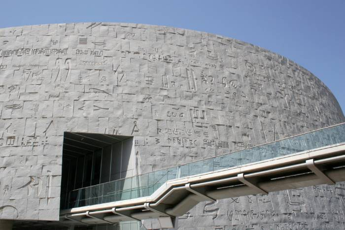 Exterior view of the Bibliotheca Alexandrina featuring its iconic granite façade engraved with ancient scripts.