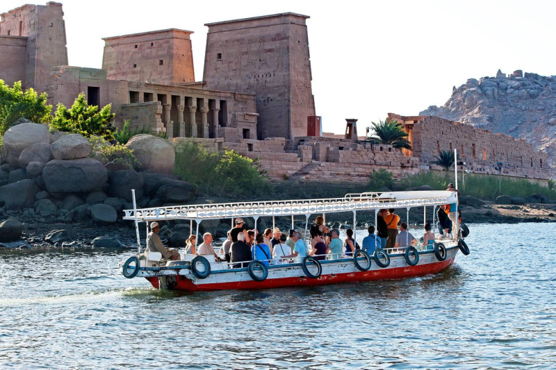 Tourists sailing on the Nile River past the Temple of Philae in Aswan, Egypt.